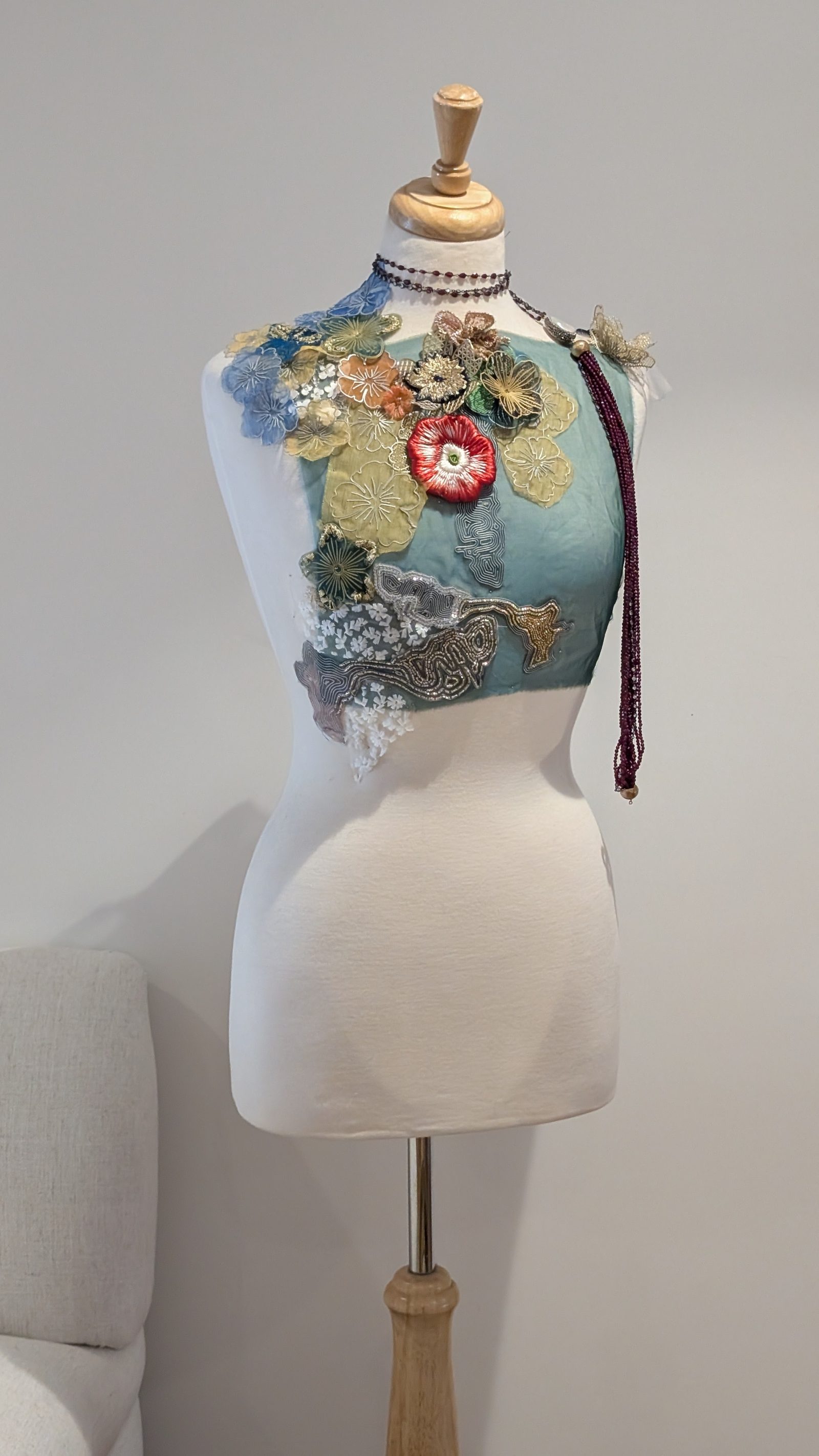 Textile et ornement — Le buste des essais : broderies, fleurs et perles épinglées à hauteur de corps