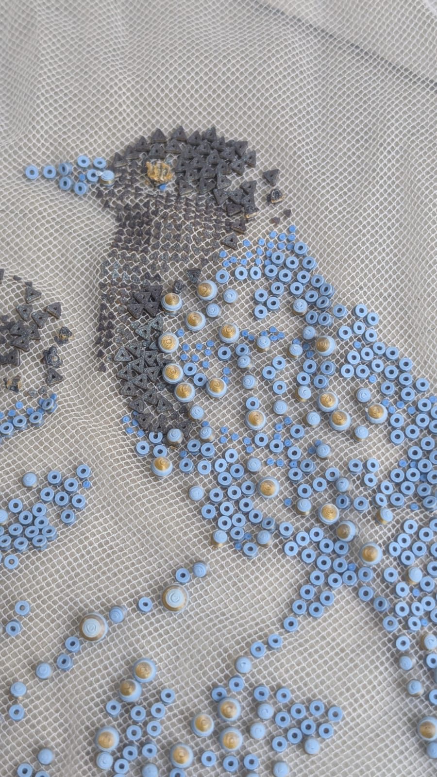 Re-former le textile — De près : la tête en triangles mats, le corps en rondelles bleues et or
